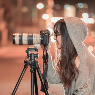Photo d'une femme souriante prenant une photo via un appareil sur trépied