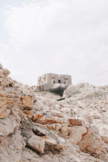 Fort de Pomègues - Amas de roches grises au premier plan, suivi d'un fort de couleur gris au second plan